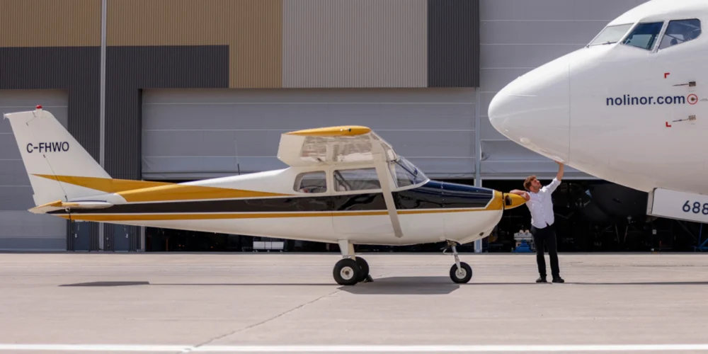 Un homme en chemise blanche examine le nez d'un gros avion, tandis qu'un petit avion à hélice est garé à côté.