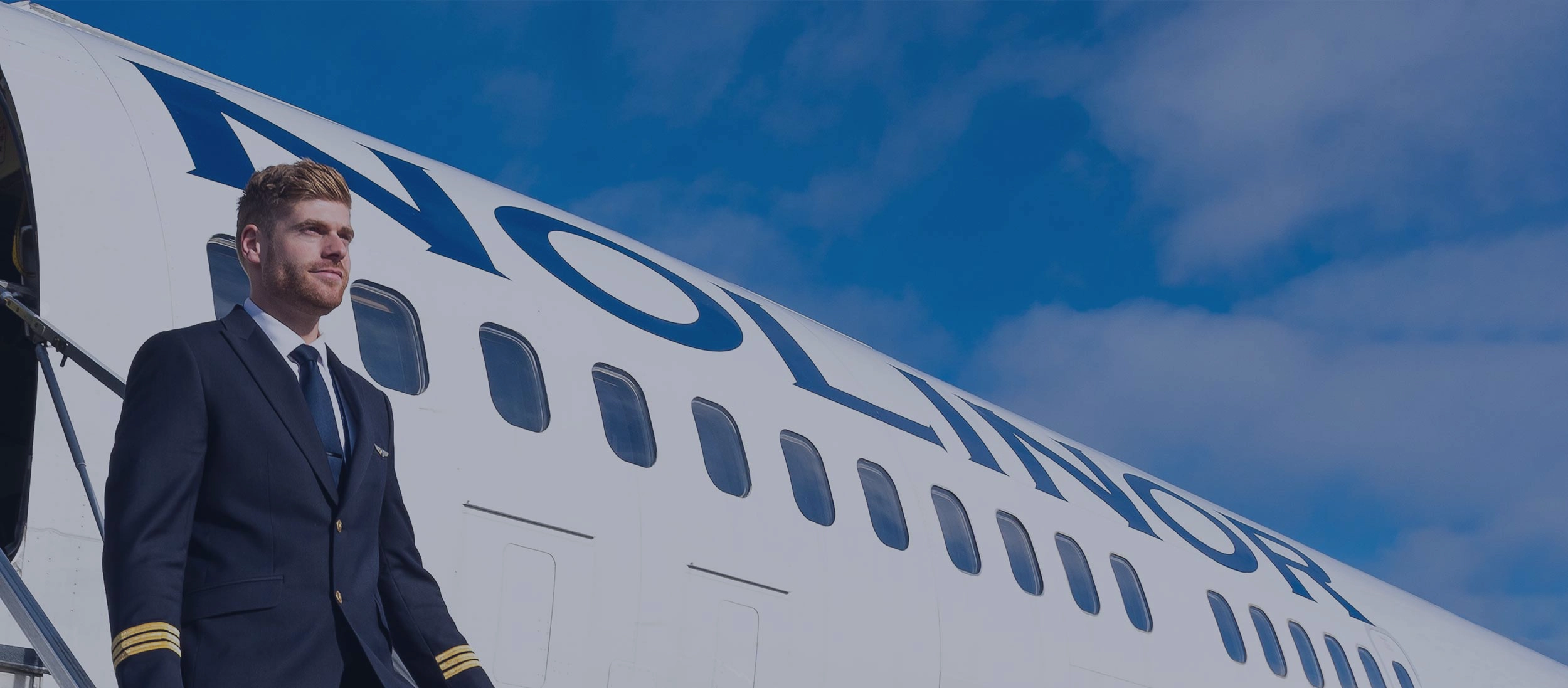 Pilot in uniform exiting a Nolinor aircraft via stairs, with a blue sky background.