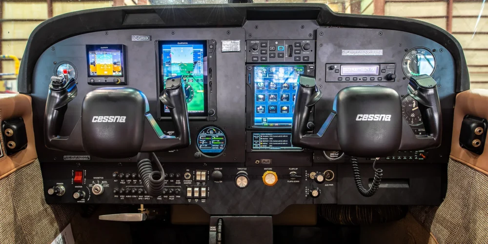 Cockpit d'un avion Cessna avec plusieurs écrans affichant des données de vol, commandes de pilotage et instruments de navigation.
