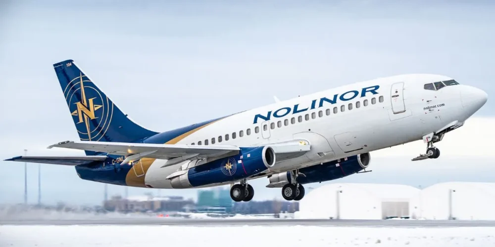 Nolinor Airlines plane takes off from a snowy runway, showcasing its blue and gold livery against a cloudy sky.